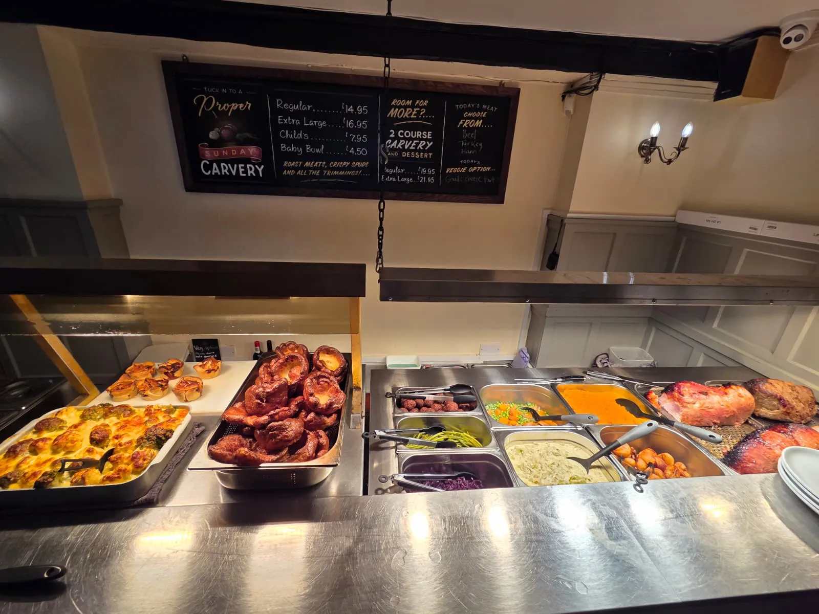 The Sunday carvery servery at The Tavern Inn, laid out with roast joints, Yorkshire puddings and seasonal veg beneath the carvery price board